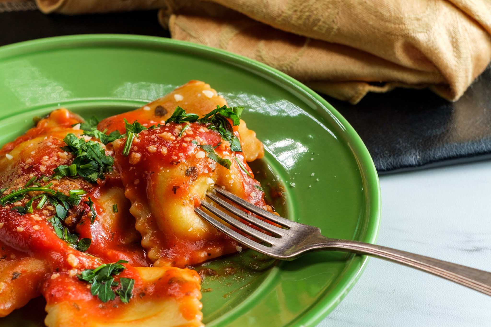 Fresh made cheesy raviolis on a green plate at The Real Food Academy Tampa.