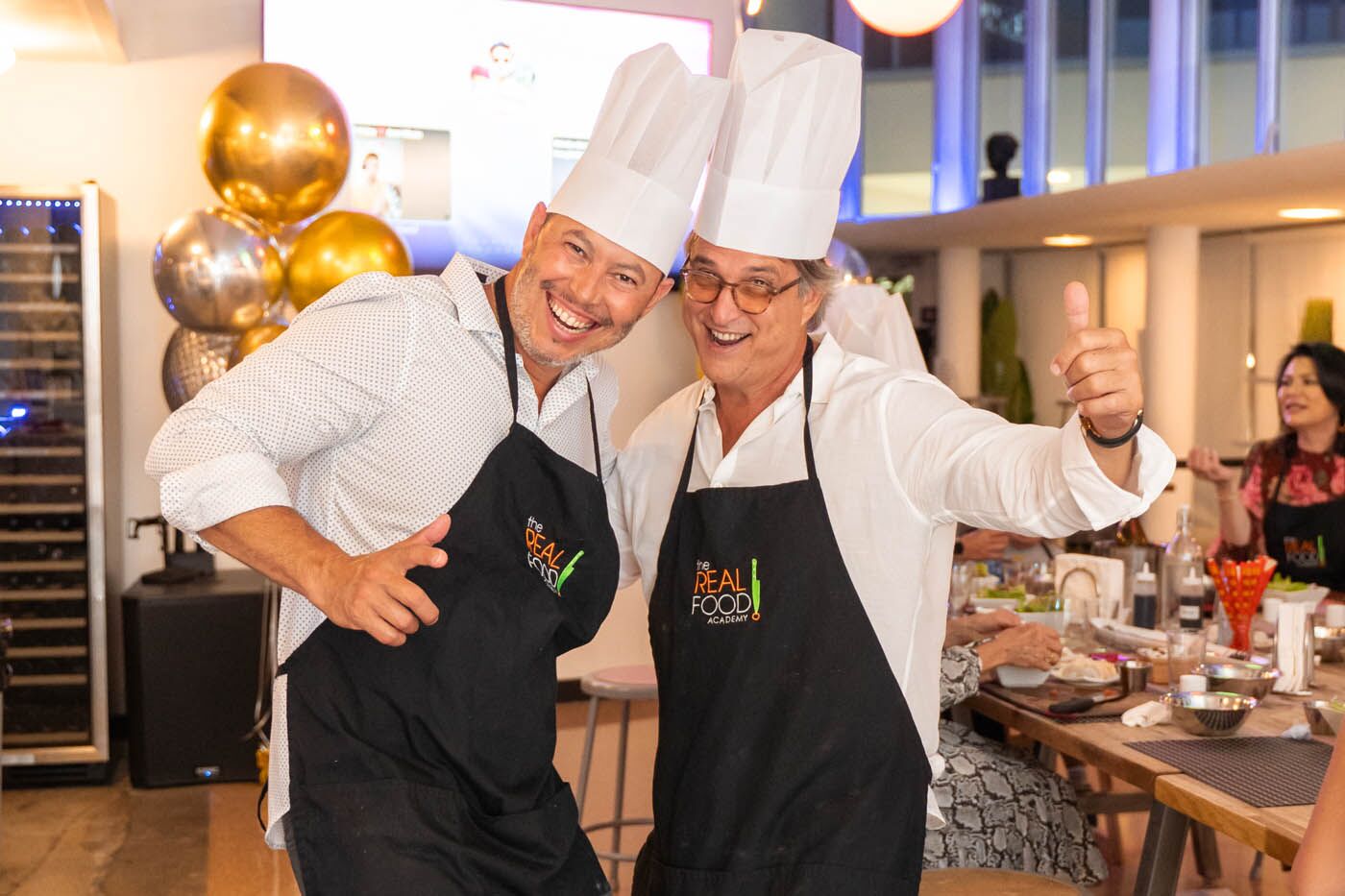Two men laughing while having a drink at The Real Food Academy adult birthday party place.